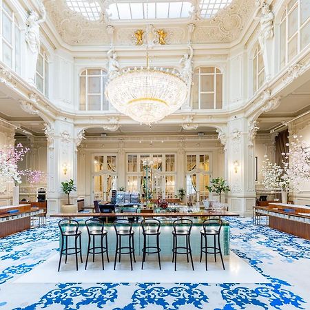 Grandhotel Pupp Karlovy Vary Esterno foto The photo shows an elegant interior space, likely a hotel lobby or a high-end establishment. The room features high ceilings adorned with ornate moldings and a large chandelier that hangs prominently from the ceiling. The space is filled with natural