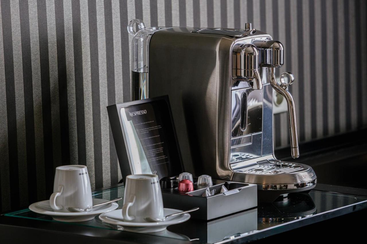 Grandhotel Pupp Karlovy Vary Esterno foto The photo shows a sleek, modern coffee machine positioned on a countertop. The machine has a shiny, metallic finish and is equipped with a faucet for dispensing coffee. Next to the coffee machine, there are two white coffee cups on small saucers. In 