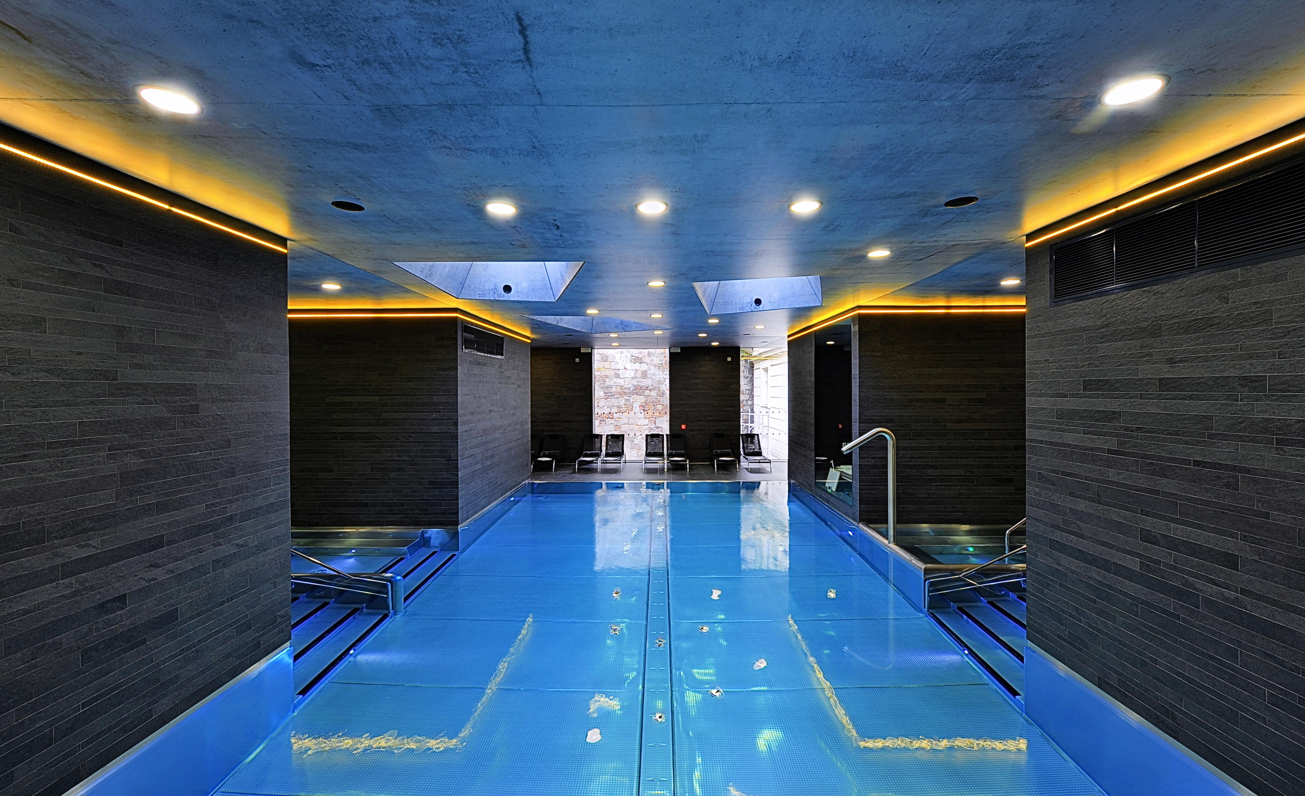 Grandhotel Pupp Karlovy Vary Esterno foto The photo shows a modern indoor swimming pool area. The pool features a striking blue surface and is surrounded by sleek, dark walls. Ambient lighting, including soft yellow or warm lights along the edges, enhances the contemporary aesthetic. There a