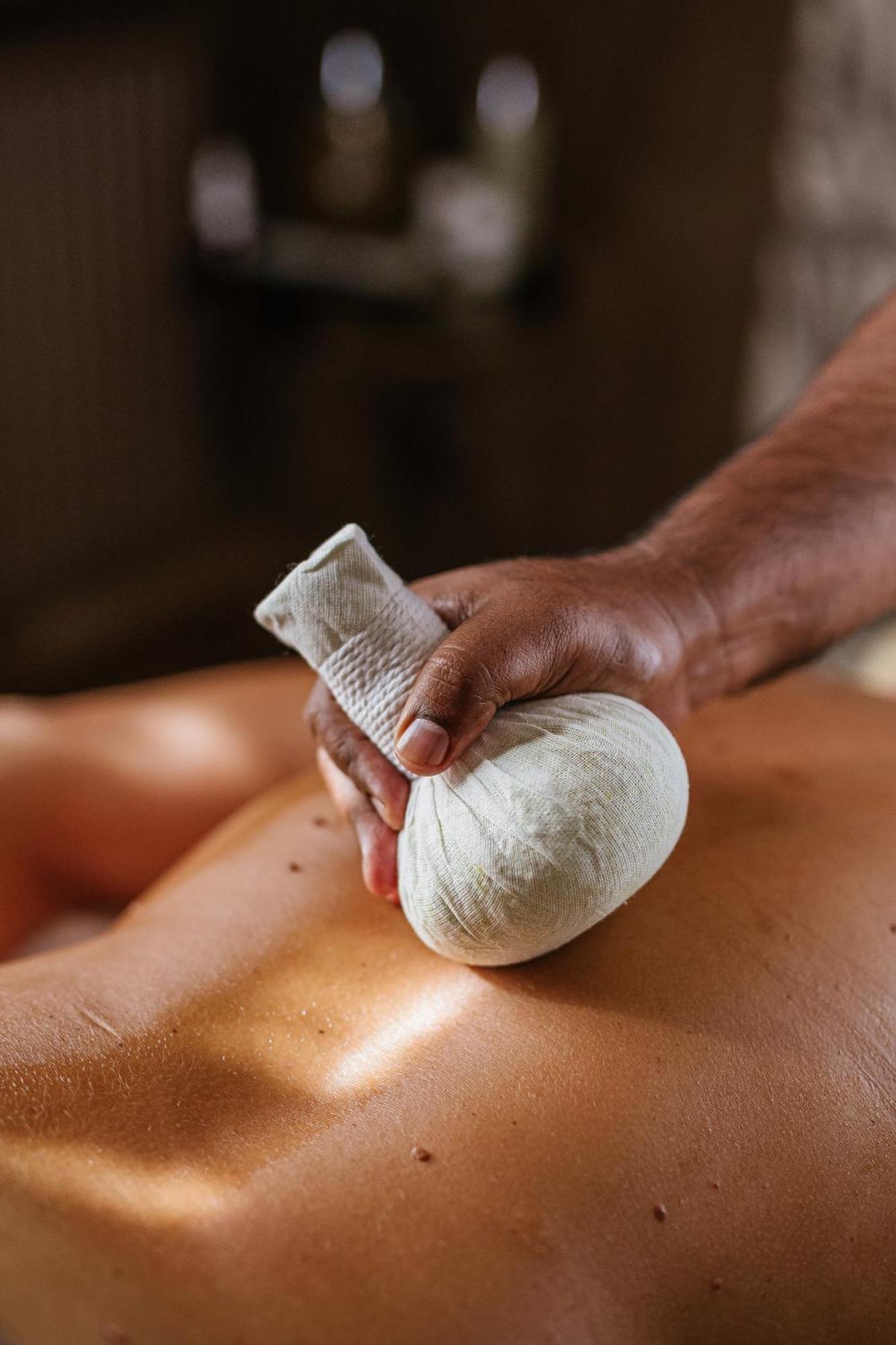 Grandhotel Pupp Karlovy Vary Esterno foto The photo shows a close-up of a hand holding a small, round compress, often used in therapeutic massages. The compress appears to be made of cloth and is filled with various herbs or substances for warmth and relaxation. It is being applied to the ba
